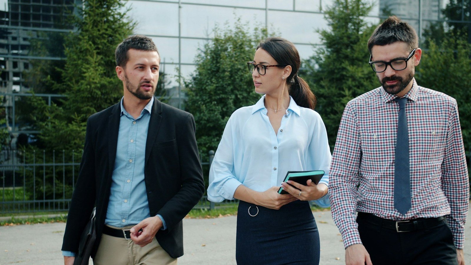 Three young professionals in business attire walking outside an office building