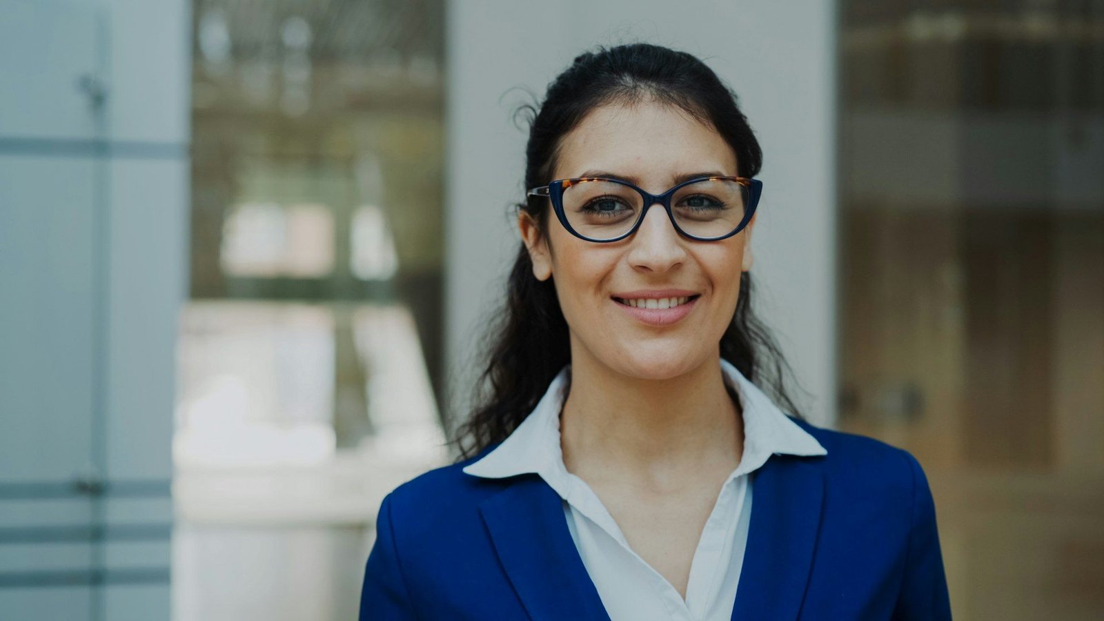 Smiling businesswoman in glasses and a navy suit in a modern office